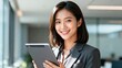 © sachintha - Smiling Young Female Professional Holding Digital Tablet in Modern Office, Confident Businesswoman Portrait