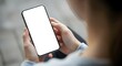 © Shikha Mony - Person holding a modern smartphone with a blank white screen in an indoor setting
