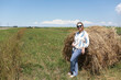 © Arkady Chubykin - Caucasian woman in blue sunglasses relaxing by hay bale in field