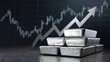 © florynstudio3 - Stacked precious metal ingots with an upward-trending arrow in front of a fluctuating financial graph