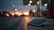 © Kdhtdg - A small solar panel rests on the ground at a gas station with blurred lights and vehicles in the background during twilight hours