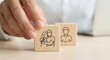 © lianlian liang - Business hand moving wooden cube with hugging couple icon next to single person block, symbolic of family protection planning, life insurance, building healthy social relationships and marriage counse