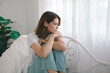 © Aphisara - The young woman sat on her bed at home, looking out the window. She appeared frustrated, confused, and unhappy, possibly experiencing personal problems such as arguments or a breakup.