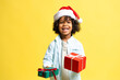 © Maria Vitkovska - Happy boy in Santa hat holding Christmas gifts on yellow background