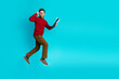 © deagreez - Jumping stylish man with red sweater holds clipboard against a bright blue studio background