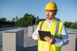 © zinkevych - Engineer wearing helmet and safety vest inspecting solar panels with tablet