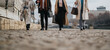 © qunica.com - Four business people walk along a city sidewalk in winter coats, carrying bags. A urban street scene shows professionals on a chilly day, dressed for work.