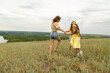 © Mariia - Mom and daughters having fun on the meadow to have a picnic to enjoy the summer day