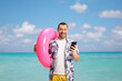© Ljupco Smokovski - Happy young man holding a swimming ring and a smartphone