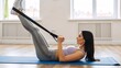 © Vasiliy - Young woman doing fitness exercises with a resistance band. Fit female athlete training legs on a yoga mat at home. Healthy lifestyle and sport concept