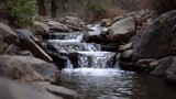 A picturesque cascade of water flows over textured rocks and ledges in a serene natural environment evoking tranquility and wilderness