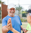 © Daniel - Senior couple playing paddle tennis or padel, outdoors in padel court enjoying and having fun together. Portrait of old man high five with his teammate