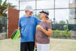 © Daniel - Portrait of couple of mature people playing padel game outdoors in a paddle tennis court together. Old man embracing mature woman teammate