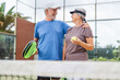 © Daniel - Portrait of couple of mature people playing padel game outdoors in a paddle tennis court together. Old man embracing mature woman teammate