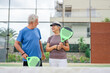 © Daniel - Portrait of couple of mature people playing padel game outdoors in a paddle tennis court together. Old man embracing mature woman teammate