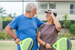 © Daniel - Portrait of couple of mature people playing padel game outdoors in a paddle tennis court together. Old man embracing mature woman teammate
