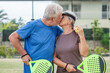 © Daniel - Portrait of couple of mature people playing padel game outdoors in a paddle tennis court together. Old man embracing mature woman teammate