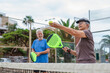 © Daniel - Portrait of couple of mature people playing padel game outdoors in a paddle tennis court together. Old man and mature woman teammate having fun enjoying