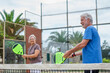 © Daniel - Portrait of couple of mature people playing padel game outdoors in a paddle tennis court together. Old man and mature woman teammate having fun enjoying