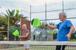 © Daniel - Portrait of couple of mature people playing padel game outdoors in a paddle tennis court together. Old man and mature woman teammate having fun enjoying