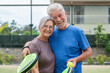 © Daniel - Portrait of couple of mature people playing padel game outdoors in a paddle tennis court together. Old man embracing mature woman teammate looking camera