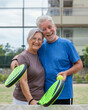 © Daniel - Portrait of couple of mature people playing padel game outdoors in a paddle tennis court together. Old man embracing mature woman teammate looking camera