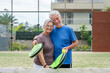 © Daniel - Portrait of couple of mature people playing padel game outdoors in a paddle tennis court together. Old man embracing mature woman teammate looking camera