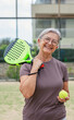 © Daniel - One old mature senior woman in padel court outdoors looking at the camera having fun holding paddle tennis racquet smiling and enjoying after game