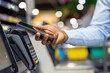 © Liubomir - Person making a digital transaction using a mobile phone at a checkout counter, showing modern nfc technology for seamless cashless payment in a retail environment