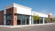 © mila103 - A building with a modern design stands in a commercial area. The storefront has large windows and is surrounded by an empty parking lot. It is a sunny day with blue skies.