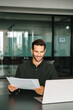 © Stock 4 You - Smiling latin business man salesman working on laptop computer reading financial contract document in office workplace. Young manager businessman specialist doing paperwork analysing on pc. Vertical
