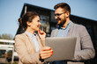 © Novak - Professional business man and woman in formal suits standing outside a modern office building