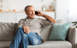 © Prostock-studio - Happy Senior Man Talking On Mobile Phone Looking Aside Sitting On Couch At Home. Grandpa Communicating Having Cellphone Conversation Indoor. Modern Communication, People And Gadgets Concept