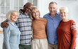 © Prostock-studio - Portrait of multiethnic group of happy senior friends men and women in casual outfits enjoying time together, cheerfully smiling at camera, embracing, kitchen interior. Elderly people lifestyle