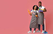 © Prostock-studio - Cleaning Service Ad. African American Couple Of Professional Cleaners With Household Supplies In Hands Pointing At Copy Space On Pink Background
