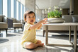 © jockermax3d - Curious Asian baby reaching for potted plant in sunny living room