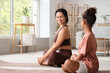© Pixel-Shot - African-American mother with her teenage daughter sitting on yoga mats at home