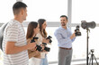 © Pixel-Shot - Male photographer with camera teaching young people during master class in studio