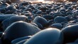 © Lycee - Close up of smooth dark pebbles on a beach with sunlight reflections