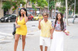 © Masakazu Tokashiki - A woman in a yellow dress walks down the street with two children. The children are holding hands and the woman is carrying a handbag. The scene is casual and relaxed