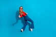 © deagreez - Stylish young woman in trendy outfit posing joyfully on a vibrant blue background