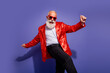 © deagreez - Energetic senior showman in red sequined jacket dancing playfully against a purple background