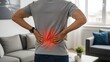 © Artfinity - Man experiencing severe lower back pain. Orthopedic health and spinal injury. Person standing in living room holding waist with red glow indicating lumbar muscle strain