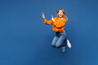 © ViDi Studio - Full body young happy fun Caucasian woman she wear yellow sweater casual clothes jump high point index finger aside on blank area isolated on plain blue background studio portrait. Lifestyle concept.