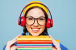 © ViDi Studio - Young happy smiling smart woman student she wear casual clothes yellow backpack bag headphones hold exercise books isolated on pastel plain light blue color background. High college lifestyle concept.