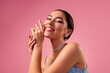 © Beauty Hero - Stunning young woman in elegant dress and jewelry against pink background, showcasing beauty and glamour