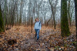 © dizfoto1973 - A woman walks through a damp, leaf-strewn autumn forest on an overcast day, surrounded by bare trees. Perfect for themes of nature walks, solitude, contemplation, or cold weather outdoor activities.