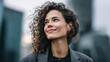 © Сreovibe - Smiling woman with curly hair looking up in a city setting
