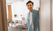 © Prostock-studio - Portrait of cheerful man welcoming inviting visitor to enter his home, happy young guy standing in doorway of modern apartment, millennial holding door looking out showing living room with hand