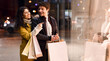 © Prostock-studio - Look here. Woman showing man fashion clothes in shop window, walking in the evening near shopping centre